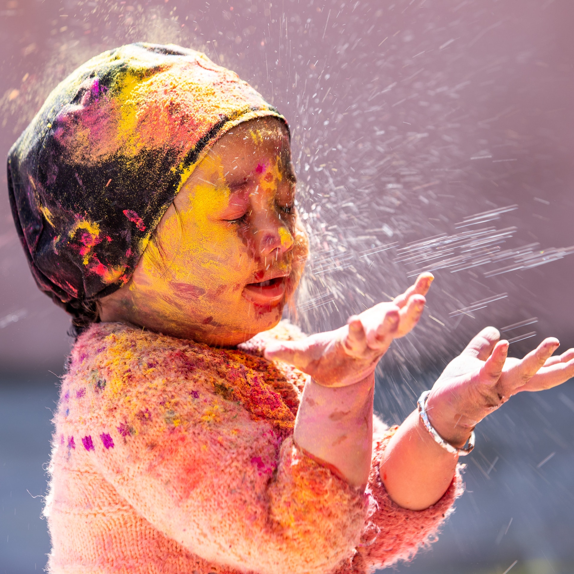 little girl playing with bright colours during holi festival